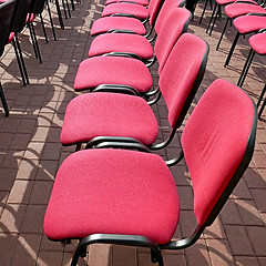 Image showing Rows of office chairs with crimson color seats outdoors