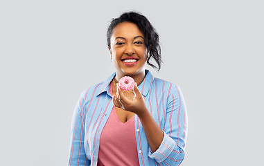 Image showing happy african american woman eating pink donut