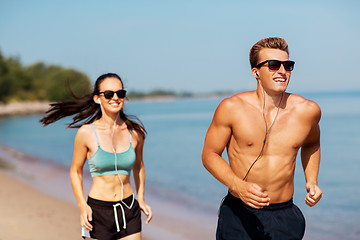 Image showing couple with earphones running along on beach