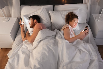 Image showing couple using smartphones in bed at night