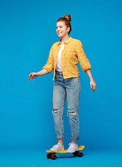 Image showing red haired teenage girl riding on short skateboard