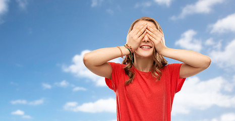 Image showing smiling teenage girl in red t-shirt over sky