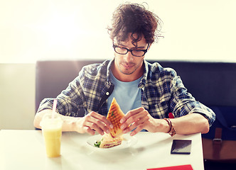 Image showing happy man eating sandwich at cafe for lunch