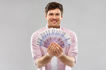 Image showing smiling young man with fan of euro money over grey