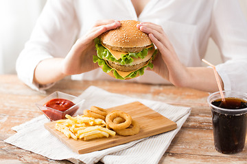 Image showing close up of woman eating hamburger at restaurant