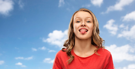 Image showing teenage girl in red t-shirt shows tongue over sky