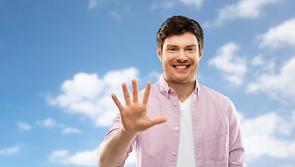 Image showing young man showing five fingers over sky