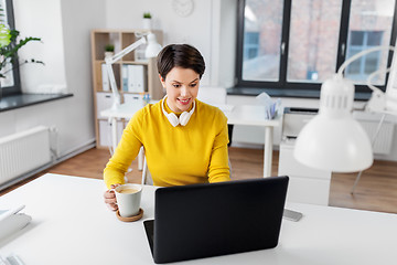 Image showing businesswoman with laptop drinks coffee at office