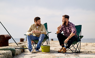 Image showing happy friends fishing and eating sandwiches