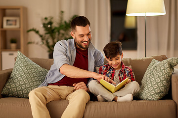 Image showing happy father and son reading book sofa at home