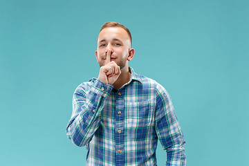 Image showing The young man whispering a secret behind her hand over blue background