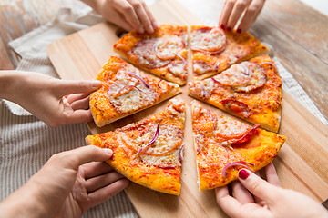 Image showing close up of hands sharing pizza on wooden table