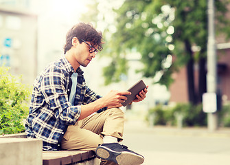 Image showing man with tablet pc sitting on city street bench