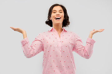 Image showing happy young woman in pajama shrugging