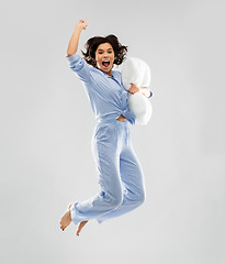 Image showing happy woman in blue pajama jumping with pillow