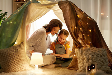 Image showing happy family reading book in kids tent at home