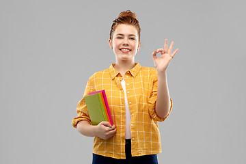 Image showing redhead teenage student girl with books showing ok