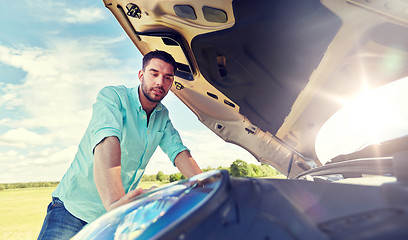 Image showing man with open hood of broken car at countryside