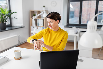 Image showing happy businesswoman using smart watch at office