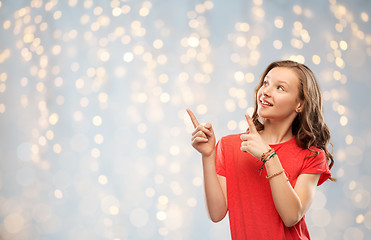 Image showing smiling teenage girl pointing fingers to something