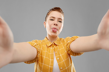 Image showing red haired teenage girl taking selfie with tongue