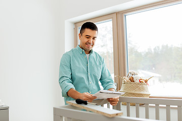 Image showing father with manual assembling baby bed at home