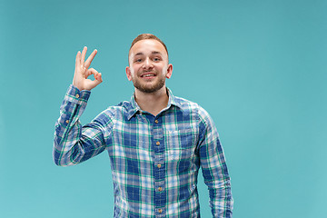 Image showing The happy businessman standing and smiling against blue background.