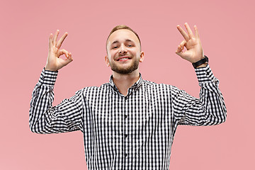 Image showing The happy businessman standing and smiling against pink background.