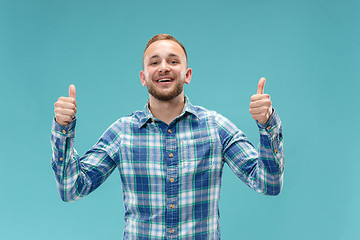 Image showing The happy businessman standing and smiling against blue background.