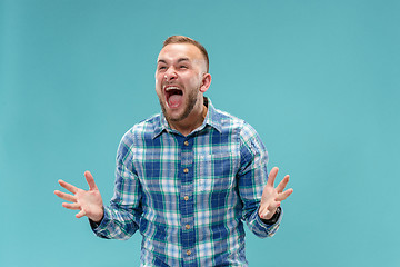 Image showing The young emotional angry man screaming on studio background