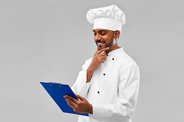 Image showing happy indian chef reading menu on clipboard