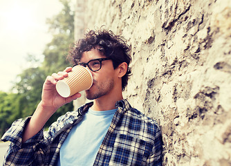 Image showing man in eyeglasses drinking coffee over street wall