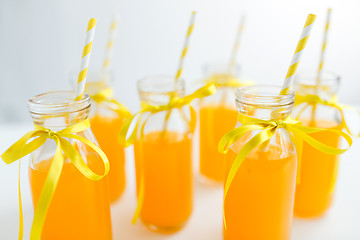 Image showing orange juice in glass bottles with paper straws