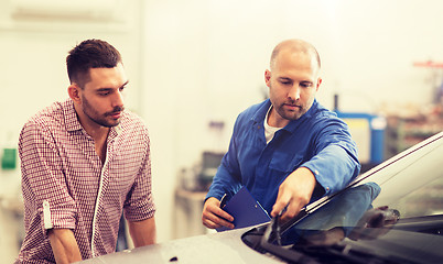 Image showing auto mechanic with clipboard and man at car shop