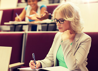 Image showing student girl writing to notebook in lecture hall