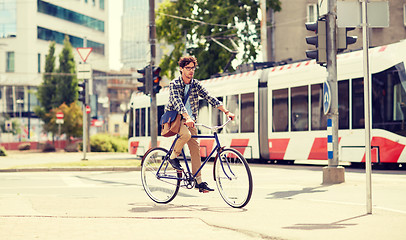 Image showing young hipster man with bag riding fixed gear bike