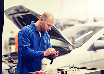 Image showing mechanic man with wrench repairing car at workshop