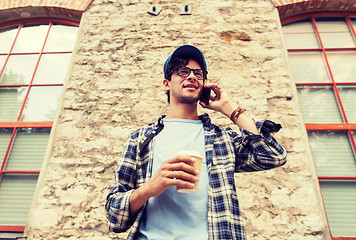 Image showing man with smartphone drinking coffee on city street