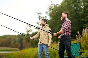 Image showing friends with fishing rods at lake or river