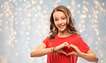 Image showing smiling teenage girl in red making hand heart