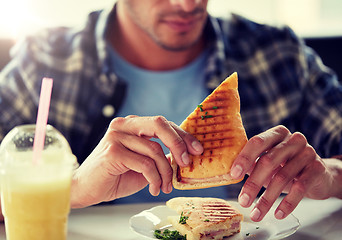 Image showing close up of man eating sandwich at cafe for lunch