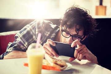 Image showing man with smartphone photographing food at cafe