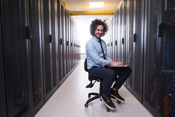 Image showing engineer working on a laptop in server room