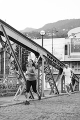 Image showing woman jogging across the bridge at sunny morning