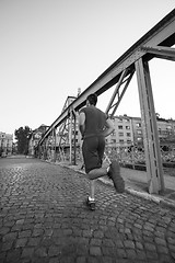 Image showing man jogging across the bridge at sunny morning