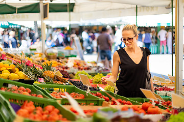 Image showing Woman buying fruits and vegetables at local food market. Market stall with variety of organic vegetable