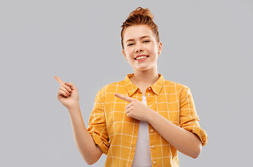 Image showing red haired teenage girl pointing fingers left