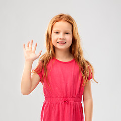 Image showing smiling red haired girl in pink dress waving hand