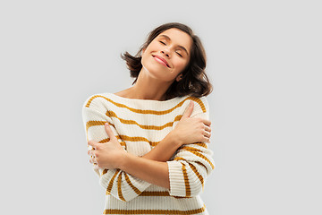 Image showing happy woman in striped pullover hugging herself