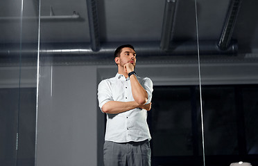 Image showing businessman looking at glass wall at night office